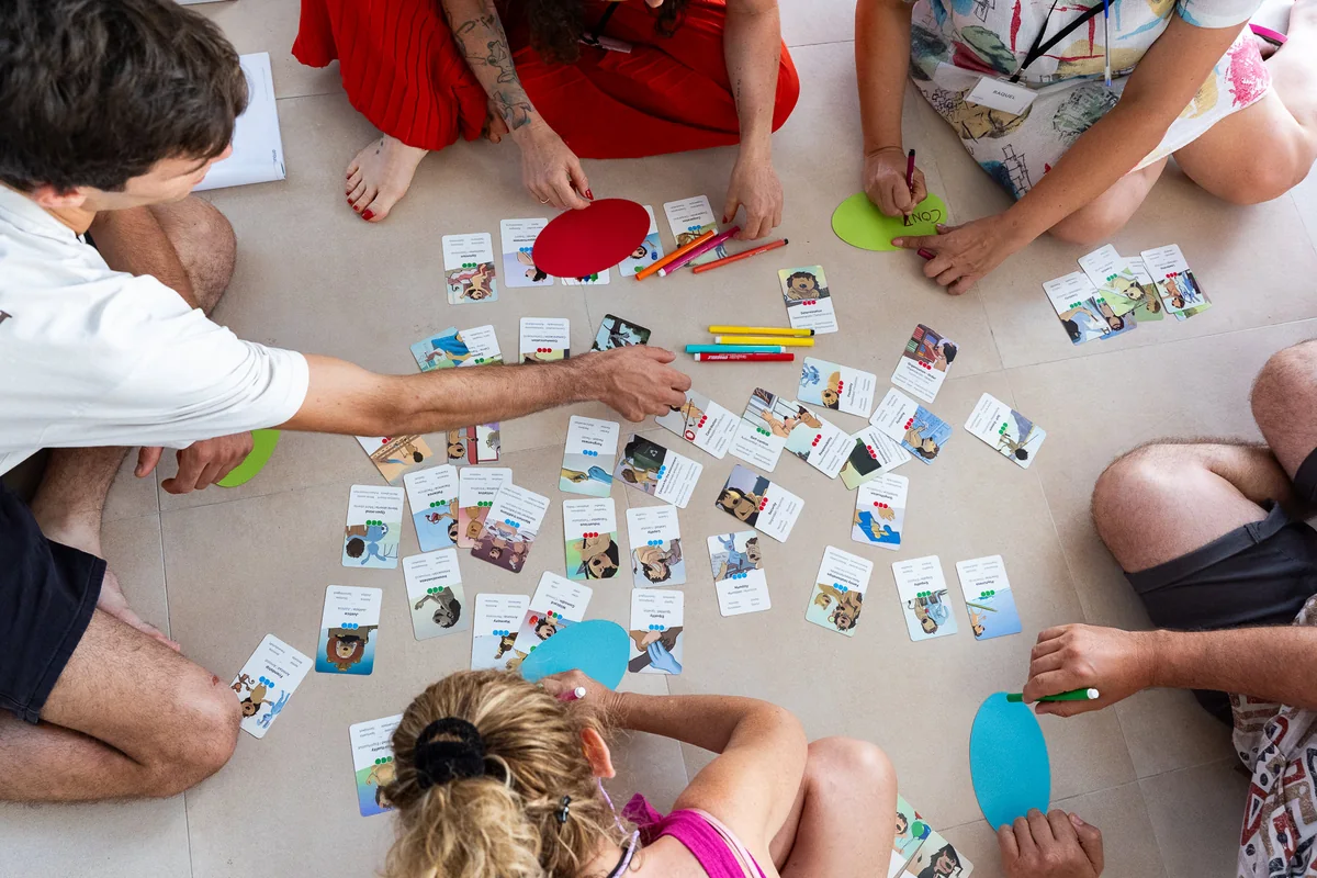 Participantes de un taller de Zinquo ordenando en el suelo las cartas de El Valor de los Valores